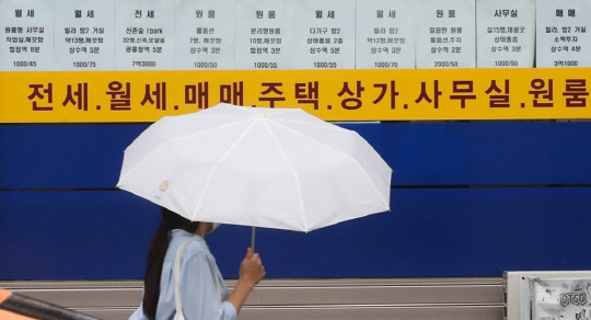 한 시민이 부동산 시세가 걸린 공인중개사 게시판 앞을 지나가고 있다.<연합뉴스>